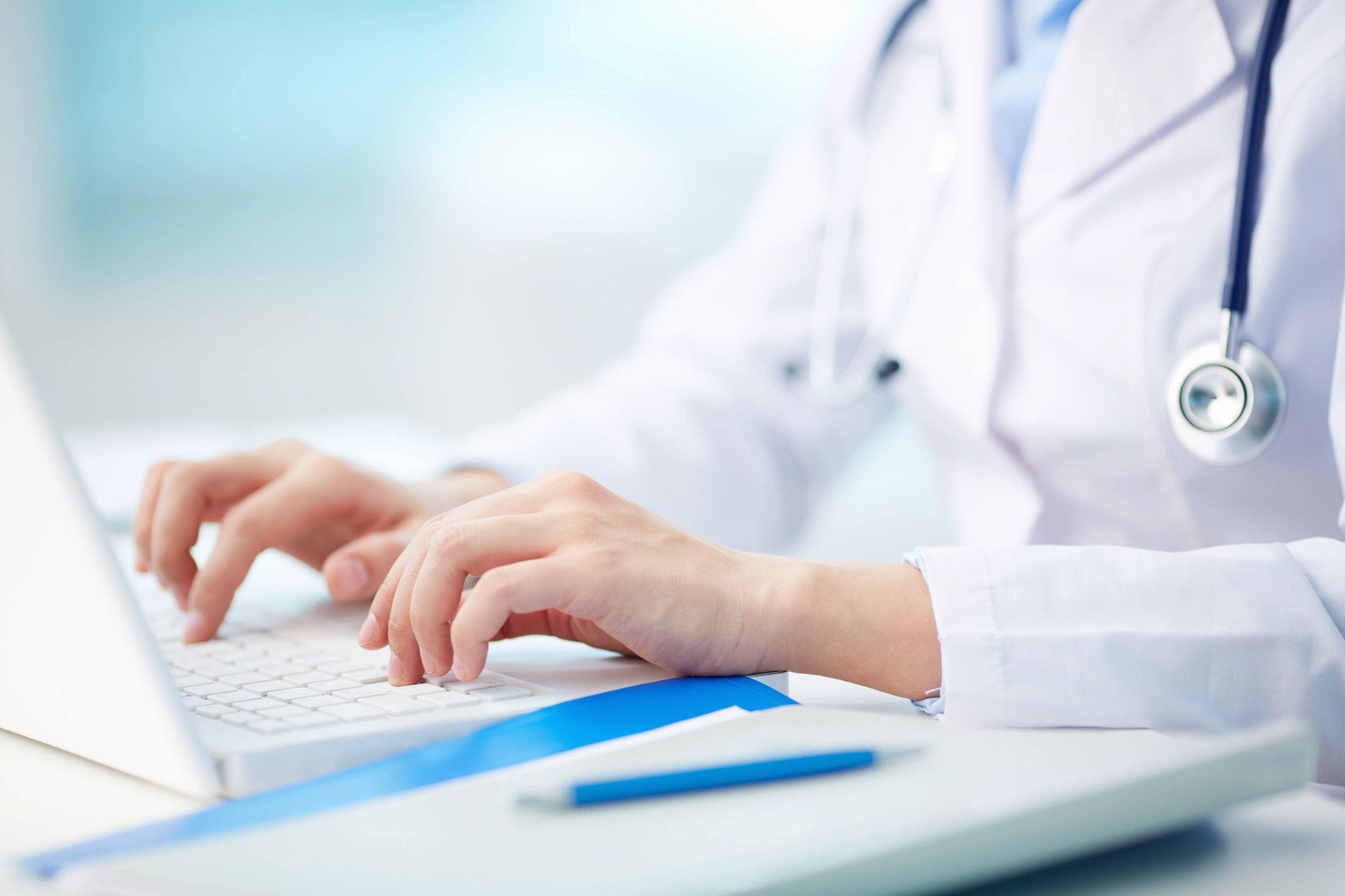 A person in white lab coat using a computer.